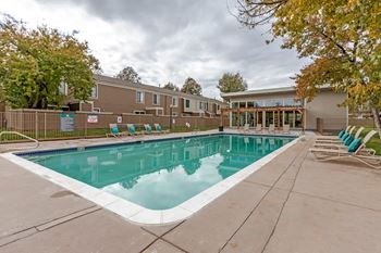 A swimming pool surrounded by a concrete floor and a wooden fence.